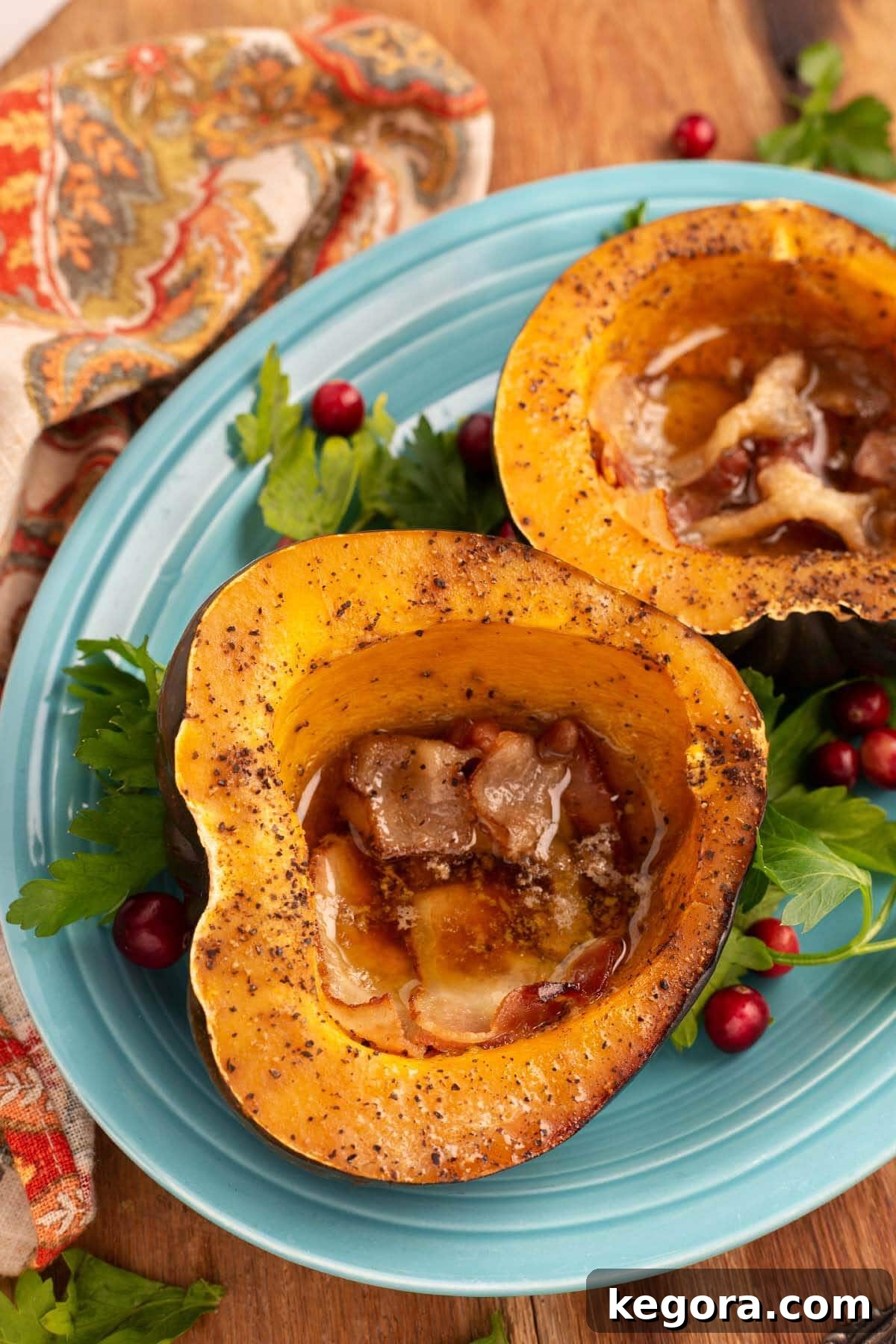 Effortless Slow Cooker Acorn Squash 2 Two halves of cooked Slow Cooker Acorn Squash on a blue plate, garnished with a sprinkle of brown sugar and a pat of melted butter, ready to be served.