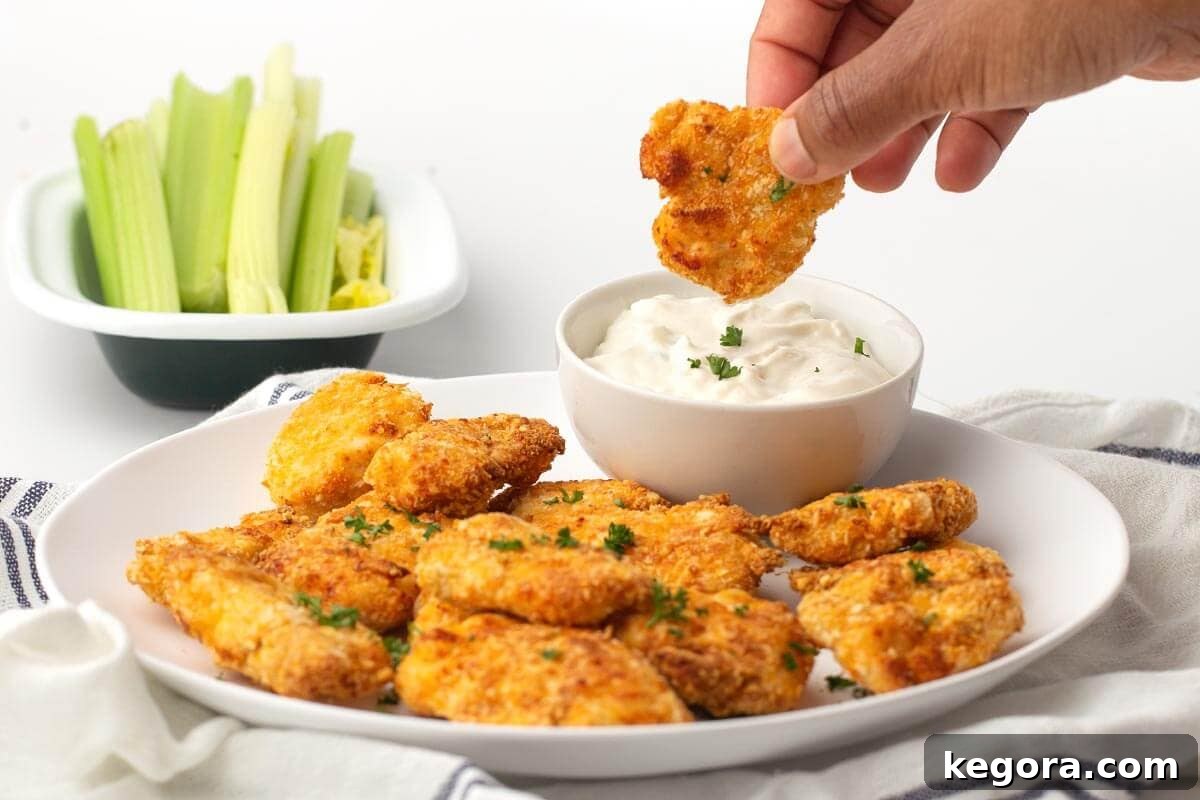 Crispy Air-Fried Nuggets 9 dipping nugget into dip with plate of nuggets