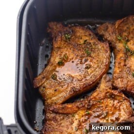 Perfectly cooked Air Fryer Pork Chops in a basket, showcasing a delicious golden crust.