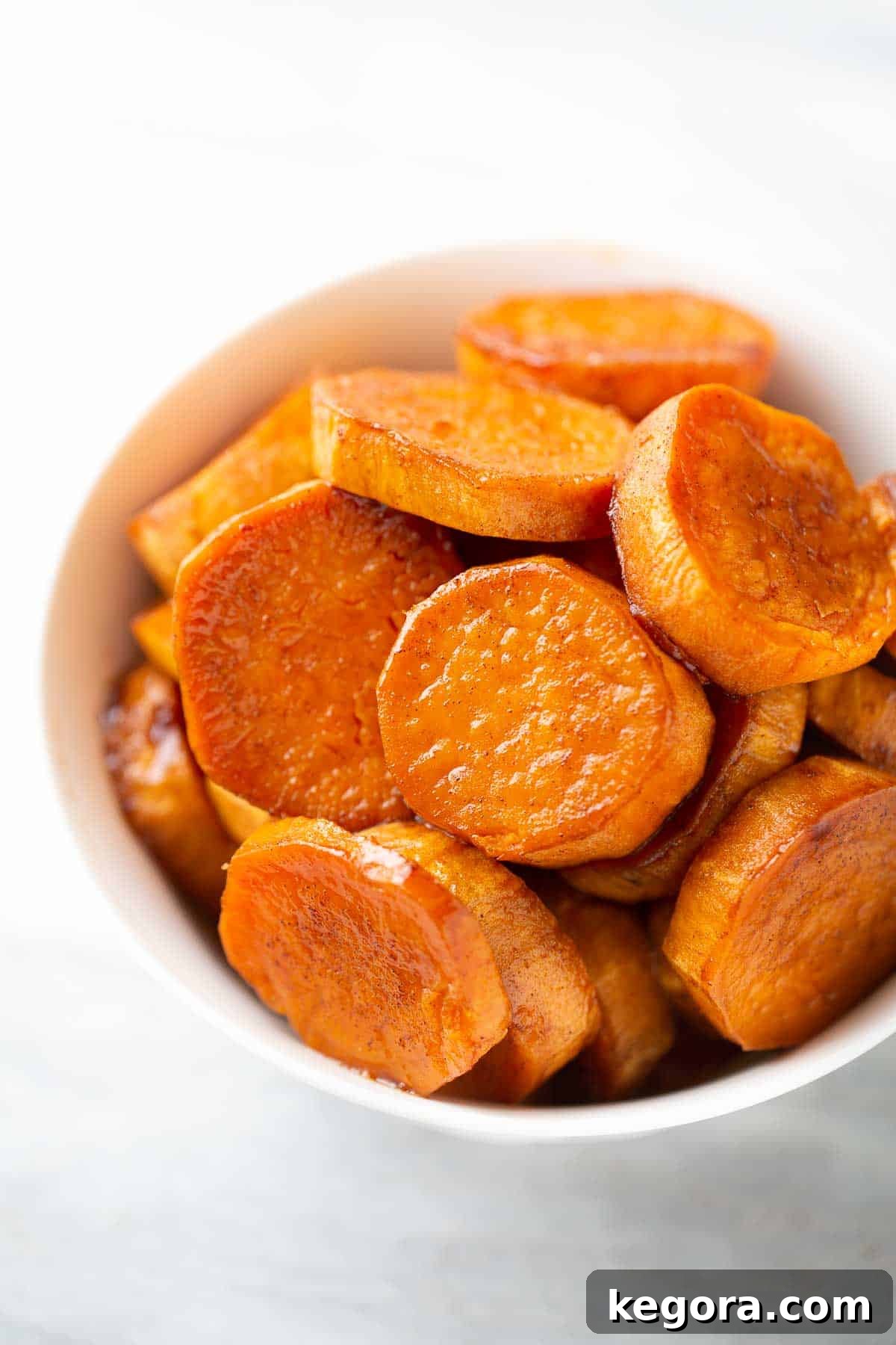 A serving bowl filled with beautifully caramelized roasted sweet potato slices, garnished with fresh herbs and ready to eat as a healthy and flavorful side dish.