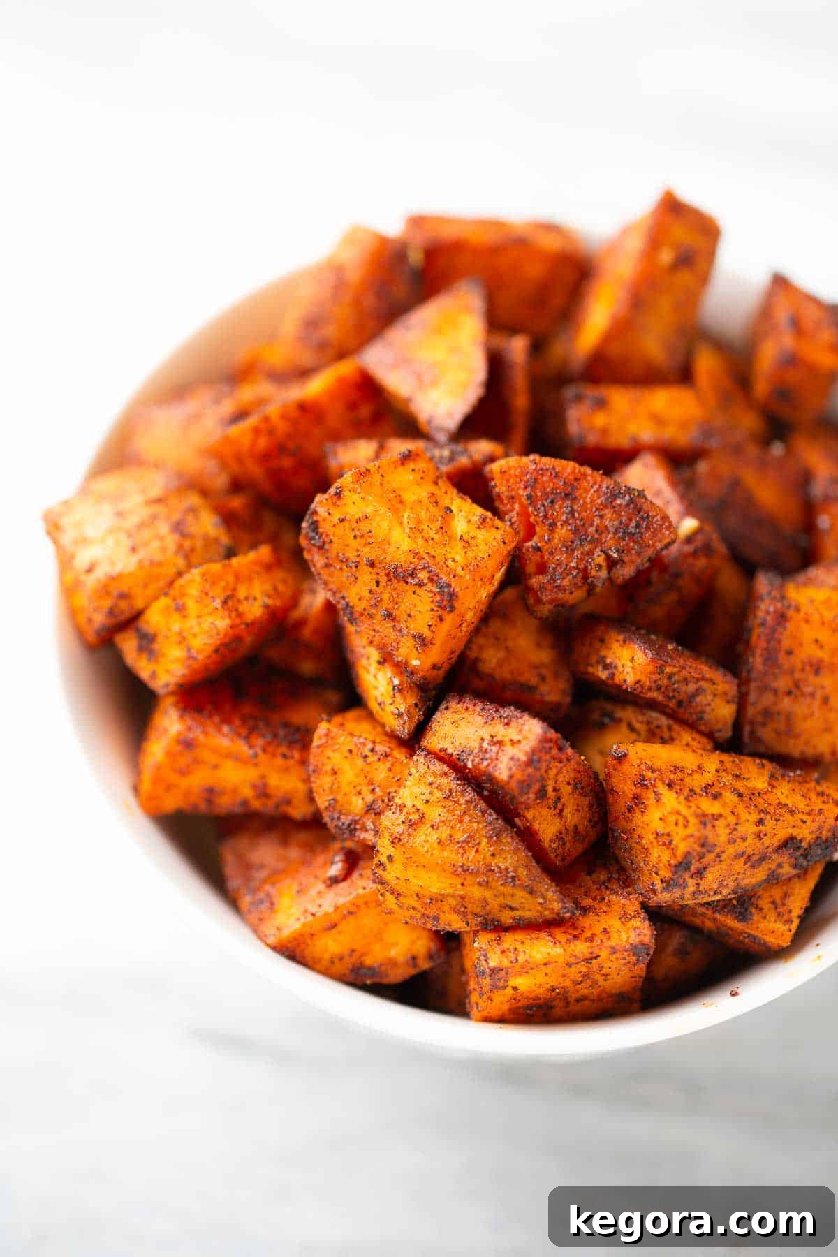 A bowl filled with bite-sized roasted sweet potato cubes, showing a tender interior and golden-brown exterior, perfect for a hearty and nutritious side dish.