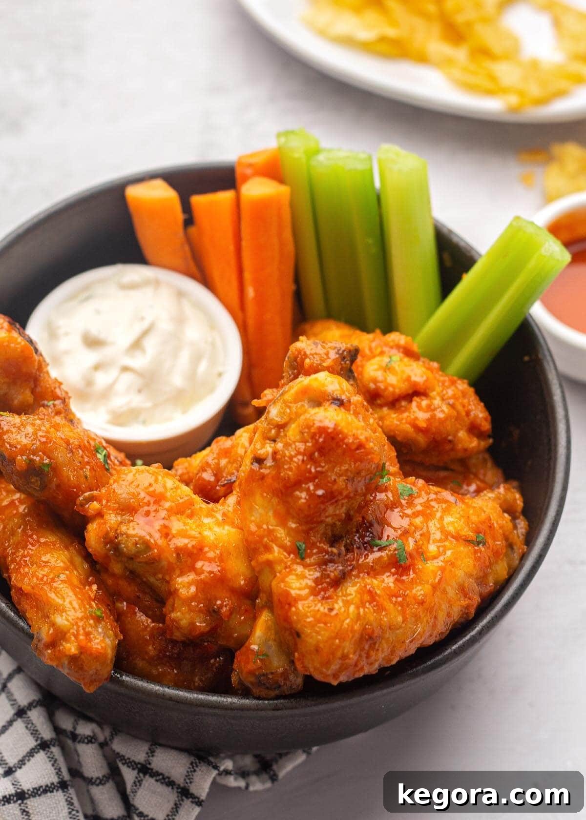 Crispy Air Fryer Buffalo Wings 2 Air Fryer Buffalo Chicken Wings in a bowl with carrots and celery, ready to be enjoyed.