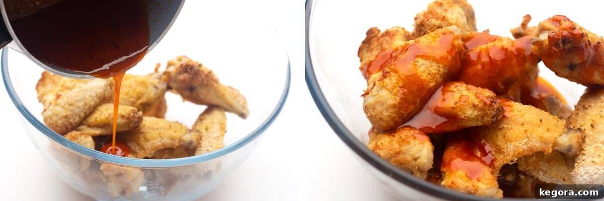 Crispy Air Fryer Buffalo Wings 9 Buffalo sauce being poured over cooked chicken wings in a bowl, then tossed to coat.