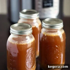 Three jars of Instant Pot Bone Broth with lids on and pressure cooker in the background