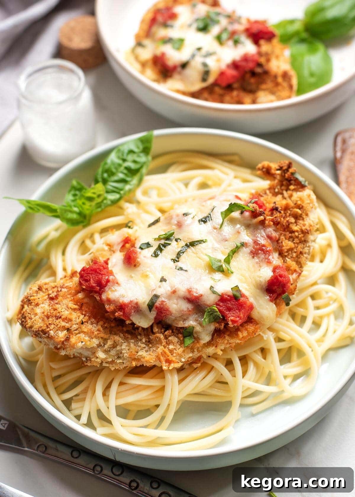 Ultimate Air Fryer Chicken Parmesan 3 Air Fryer Chicken Parmesan served on a bed of spaghetti noodles with marinara sauce.