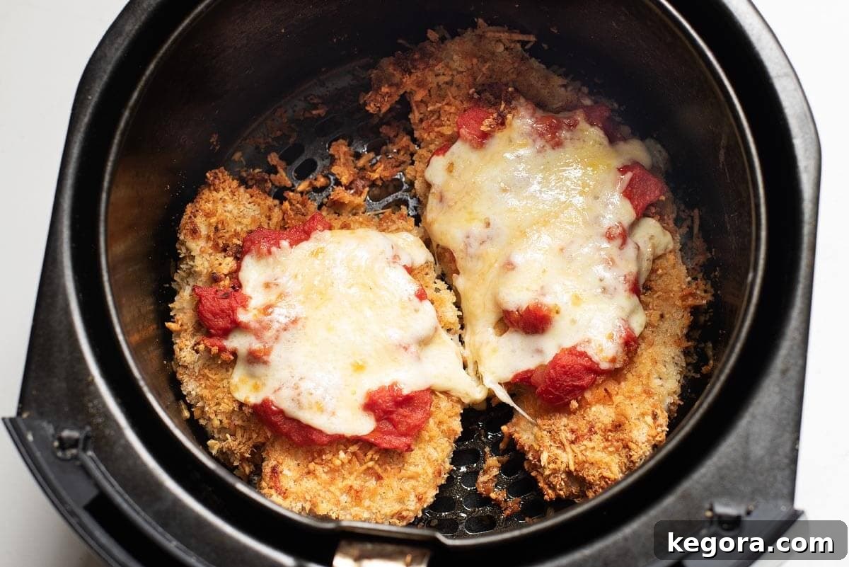 Ultimate Air Fryer Chicken Parmesan 8 Close-up of Chicken Parmesan in an air fryer basket, showing melted cheese.