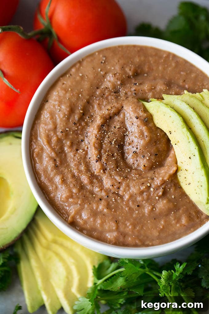 Close up of Refried Beans in small white bowl with sliced avocado