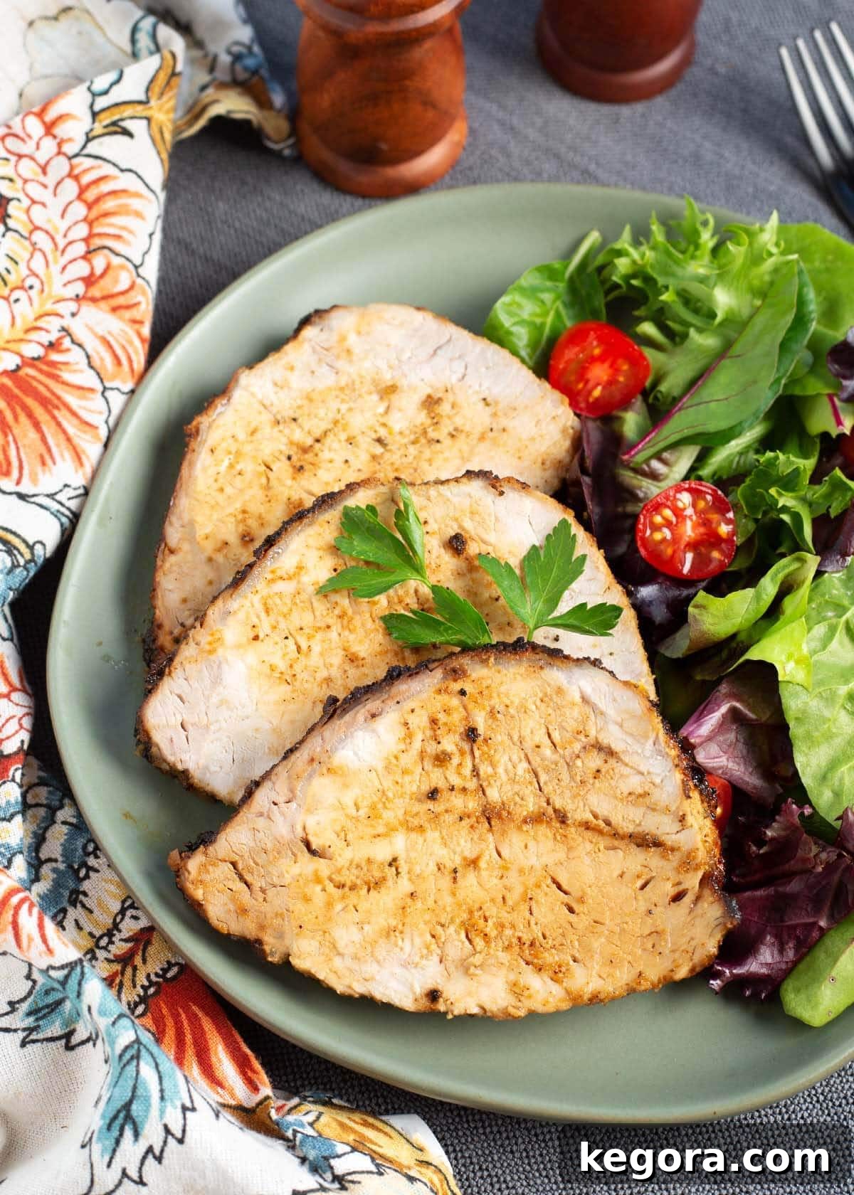 Air Fryer Pork Loin Roast slices on a plate with salad and potatoes