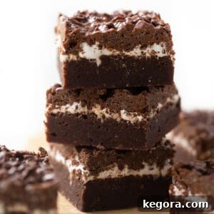 Gluten-Free Peanut Butter Brownies with a Pebbles Cereal Crunch 2 Three layered Gluten-Free Peanut Butter Crunch Brownies stacked on brown parchment paper.