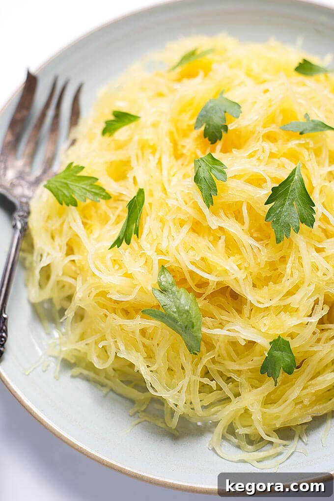 Squash Noodle Express 3 Cooked Instant Pot Spaghetti Squash threads piled on a white plate with a fork, ready to be seasoned and enjoyed.
