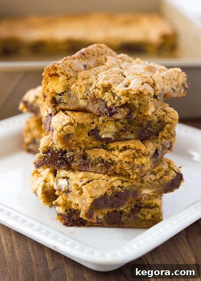 Delicious Almond Flour Blondies Gluten Free and Dairy Free 2 Stack of golden, chewy almond flour blondies on a white plate, garnished with chocolate chips and pecans.