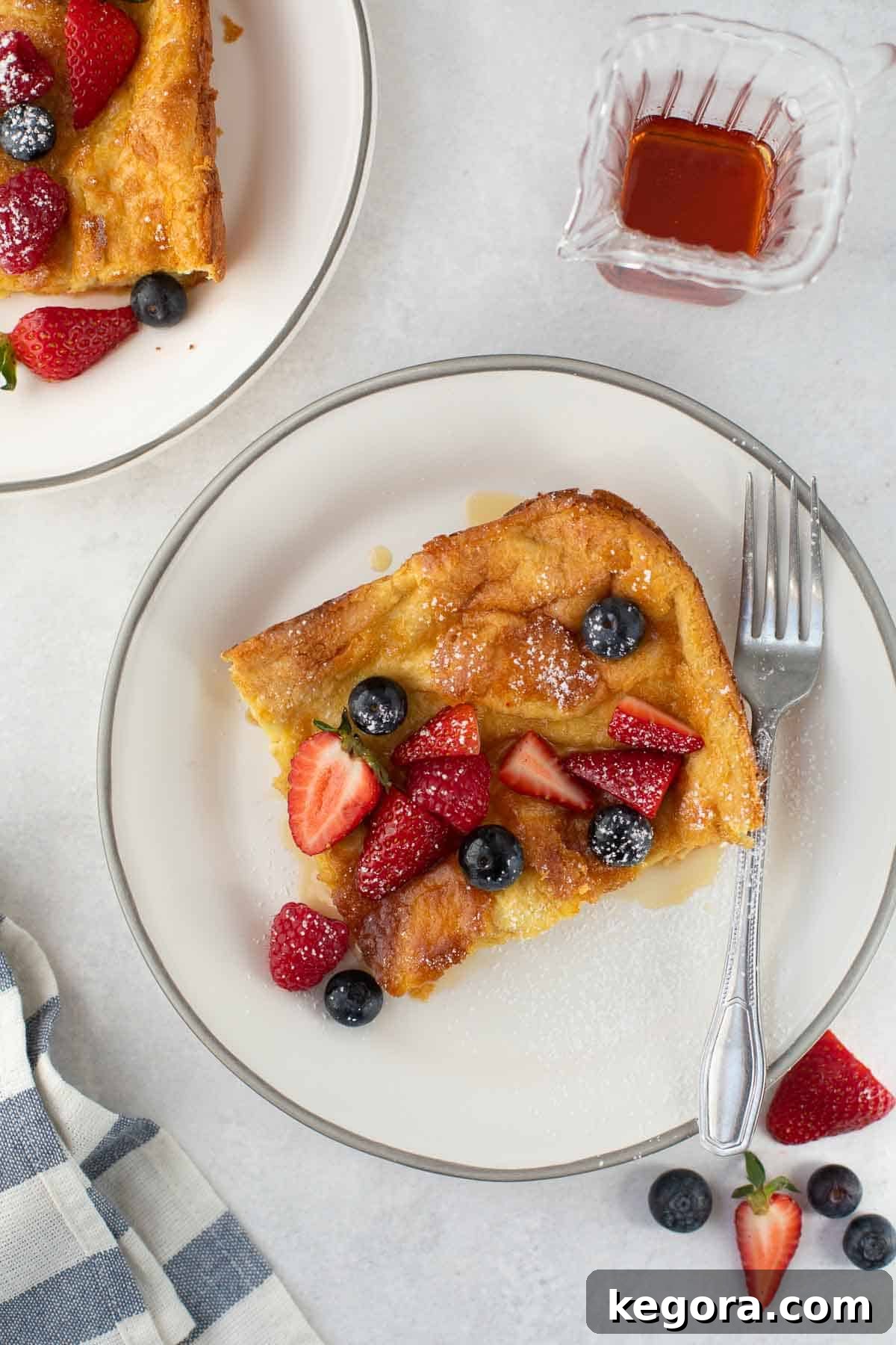 A perfectly cooked slice of gluten-free Dutch baby, golden and slightly puffed, served on a white plate with a fork.