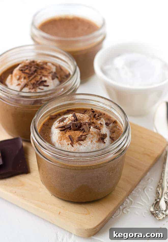 Two servings of creamy chocolate chia pudding garnished with whipped cream and chocolate shavings in glass jars, ready for a healthy and delicious breakfast