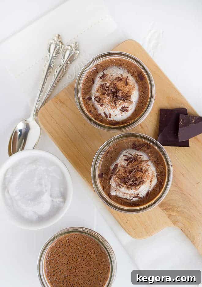 Overhead shot of two jars of chocolate chia pudding, topped with whipped cream and chocolate shavings, ready to eat after chilling overnight
