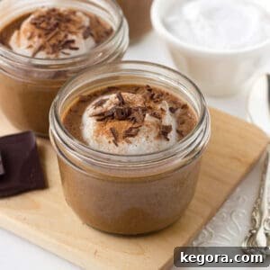 Chocolate chia pudding on a wooden cutting board with shavings of chocolate and coconut whipped cream as garnishes