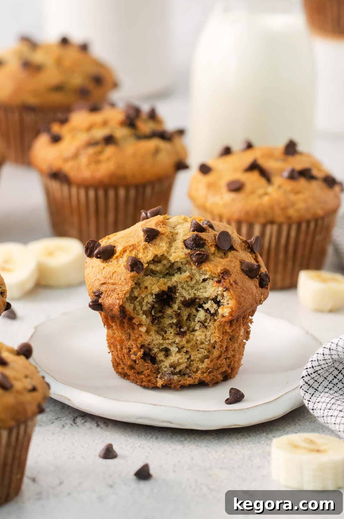 A gluten-free banana muffin on a plate with a bite taken out of it, showcasing its fluffy texture.