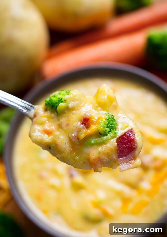 Close-up of a spoonful of creamy Loaded Broccoli Cheese & Potato Soup with visible broccoli florets, potato chunks, and melted cheese