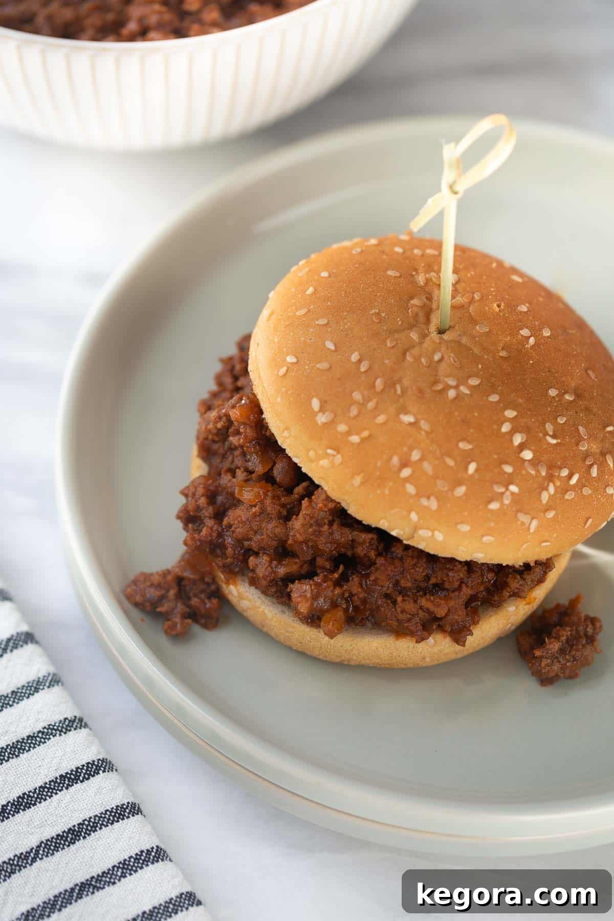 Guilt-Free Sloppy Joes 2 A delicious gluten-free sloppy joe sandwich on a toasted bun, served on a gray plate against a stylish marble background, highlighting the rich, savory filling.
