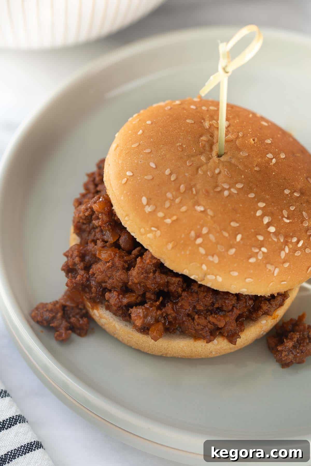 Guilt-Free Sloppy Joes 9 A close-up shot of a gluten-free sloppy joe sandwich, showing the rich texture of the seasoned meat filling on a gray plate, ready to be enjoyed.