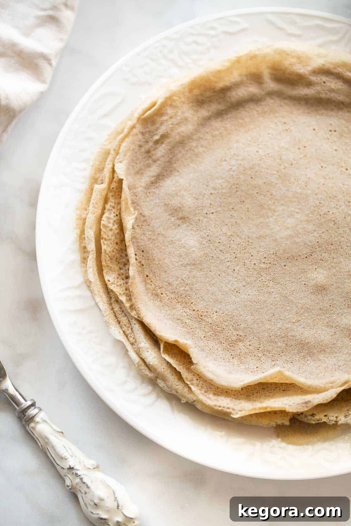 Perfectly Cooked Buckwheat Crepes close up shot of a stack of golden brown buckwheat crepes on a white plate, showcasing their perfect texture