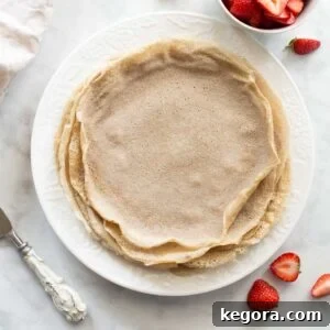 overhead shot of buckwheat crepes on white plate with strawberries, a mouth-watering breakfast