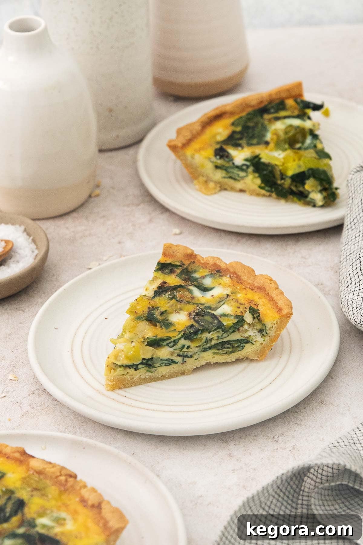 Nutty and Savory Almond Quiche 3 A perfectly sliced portion of almond flour crust quiche with visible layers of leeks and Swiss chard, served on a white plate, ready to be enjoyed.