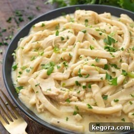 Comforting Instant Pot Chicken Noodles 7 Instant Pot Chicken and Noodles in a black bowl on wooden board next to two golden forks