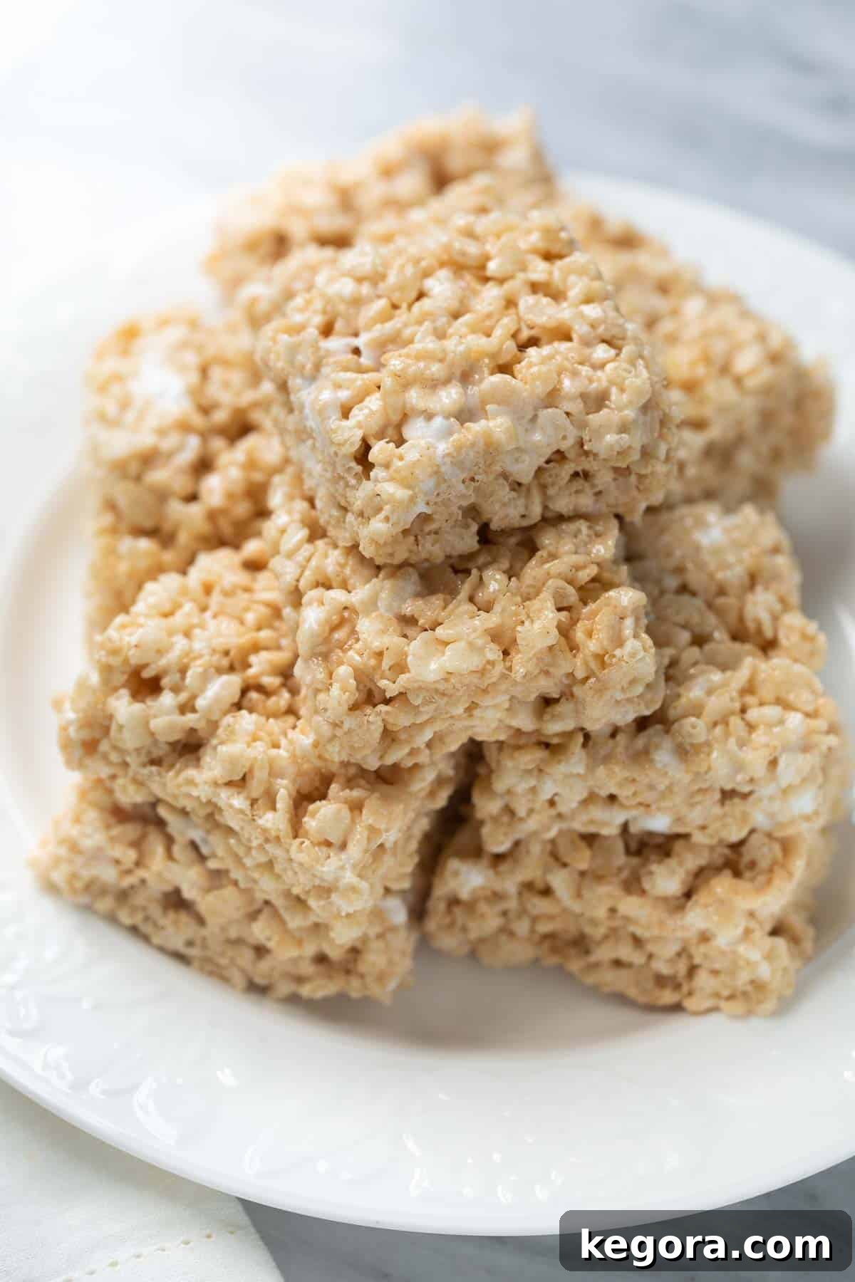 Delicious gluten-free rice krispies treats stacked neatly on a white plate, showcasing their inviting texture.