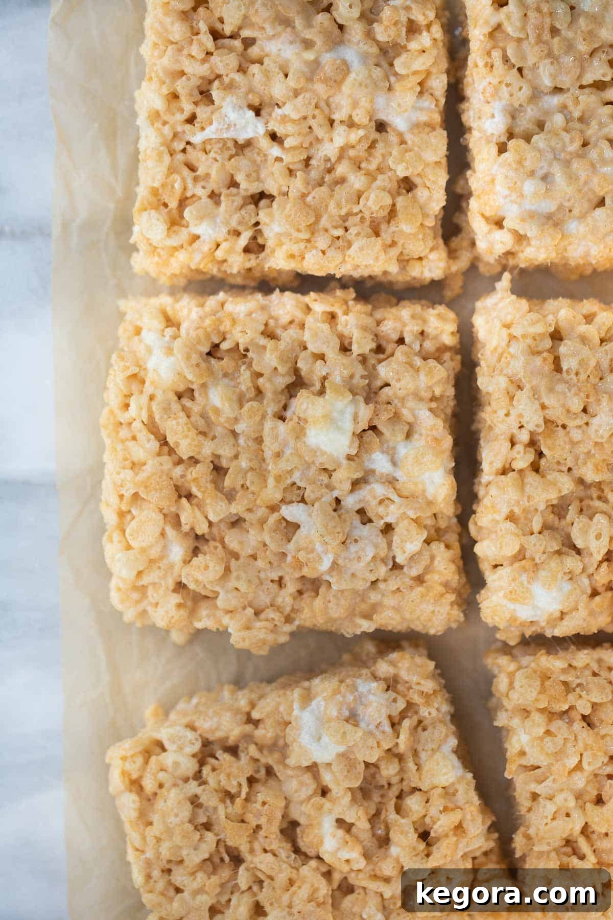 Close-up shot of perfectly cut gluten-free rice krispies treats arranged on brown parchment paper, ready to be served.