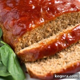 Tasty Turkey Meatloaf on white plate next to baby spinach