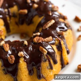Instant Pot Pecan Chocolate Chip Cake bunt pan shaped topped with pecans and chocolate syrup on white plate