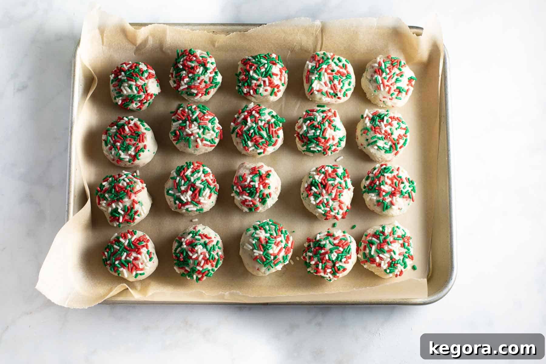 Sparkling Gluten-Free Christmas Treats 8 balls of cookie dough topped with festive sprinkles, neatly arranged and ready to chill on a baking sheet