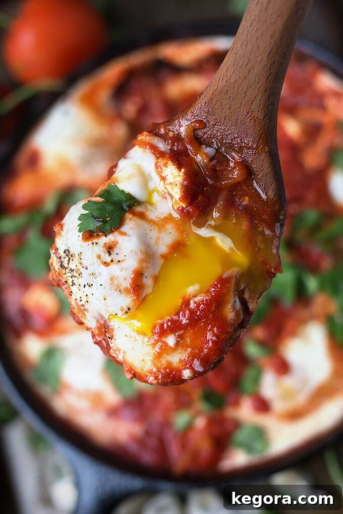 Close up of wooden spoon with Shakshouka - Eggs in Purgatory 