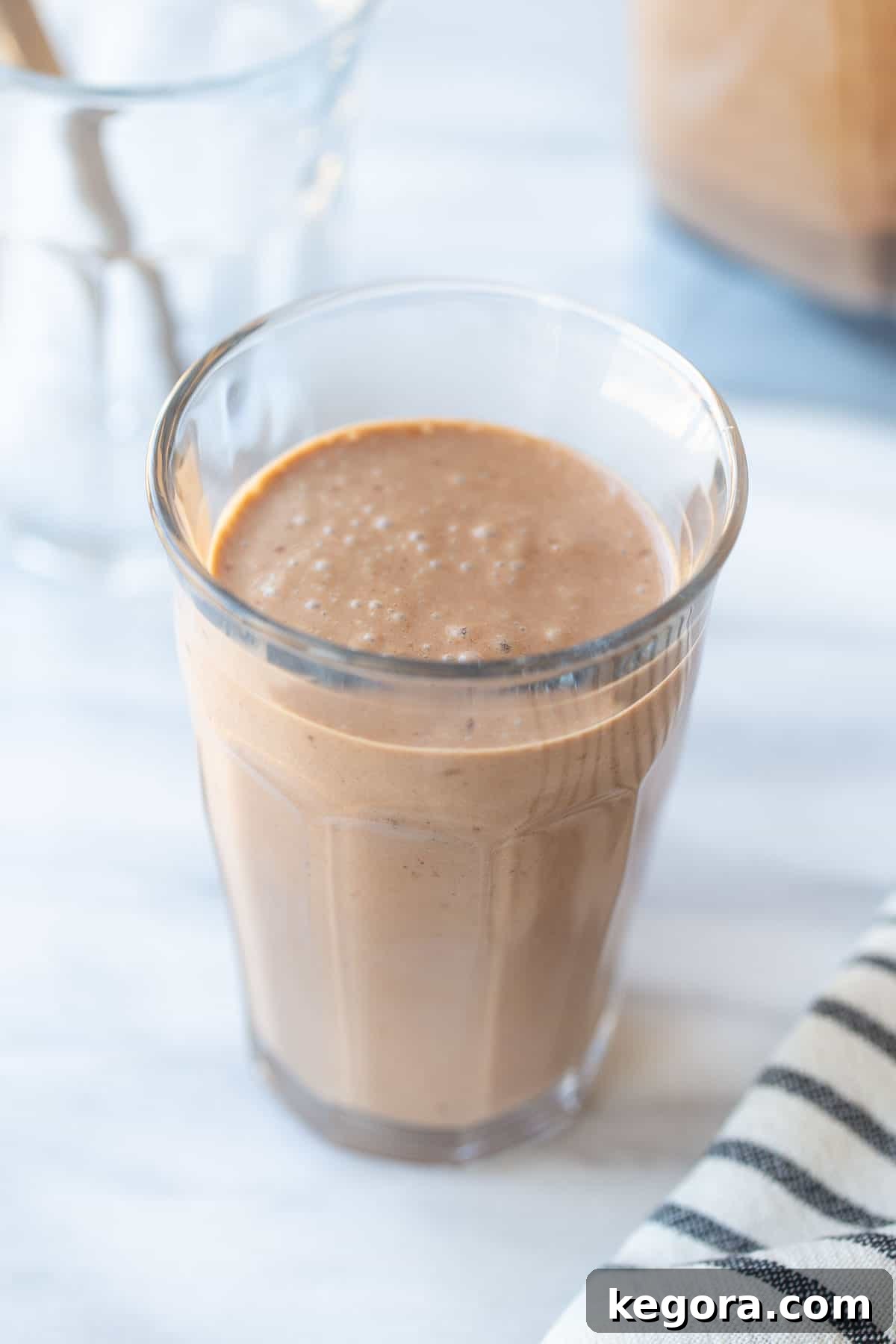 Chocolate Avocado Smoothie Thick and creamy chocolate banana avocado smoothie in a tall glass, garnished with chocolate shavings.