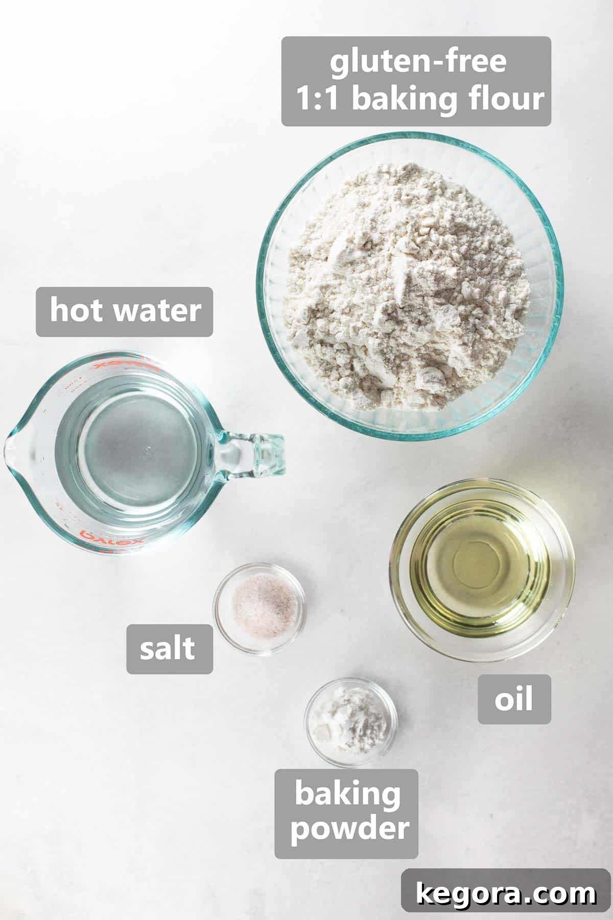 Overhead shot of labeled ingredients including gluten-free flour, baking powder, salt, oil, and hot water, laid out for making tortillas.