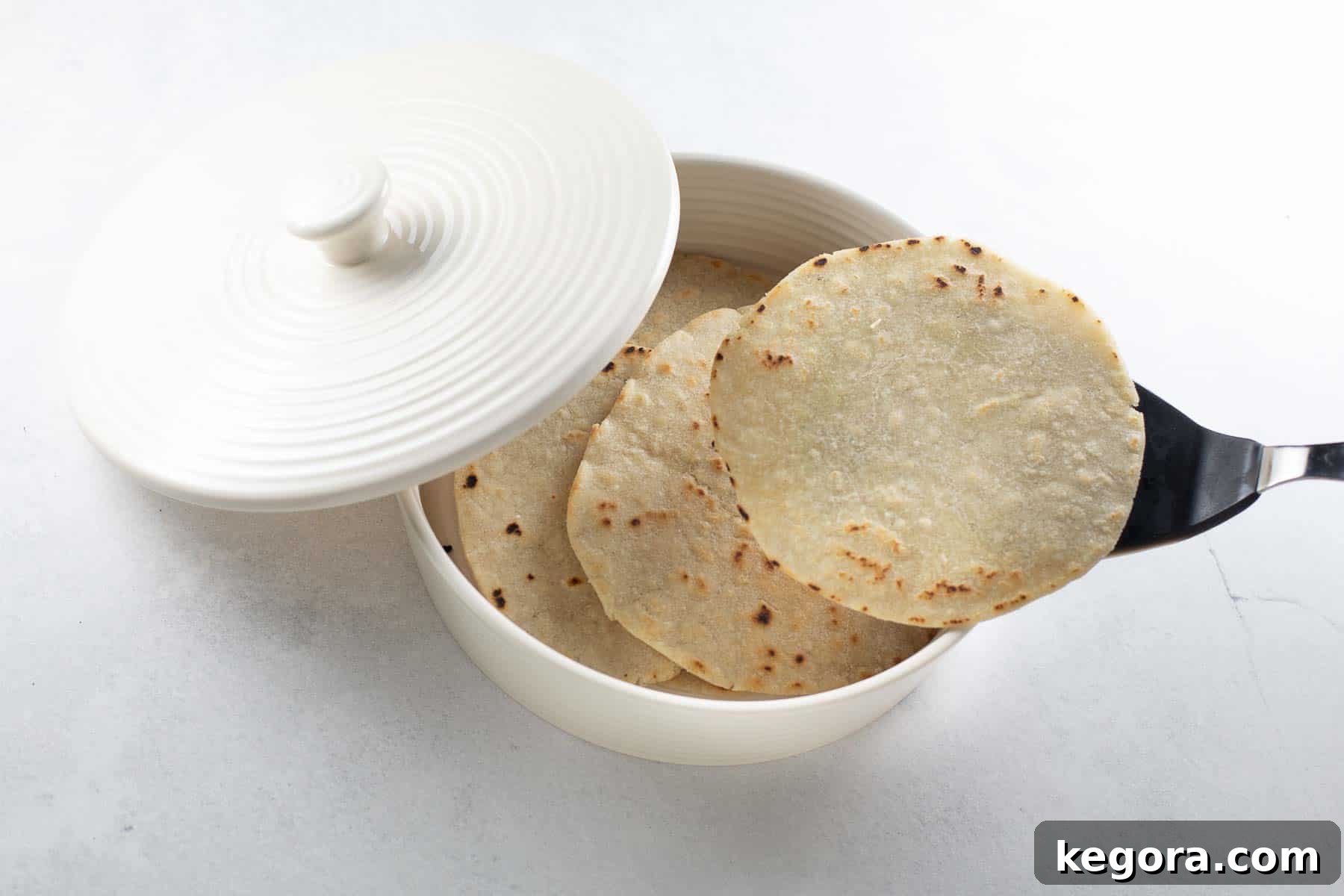 Homemade gluten-free tortillas being cooked in a hot cast iron skillet, showing slight browning.