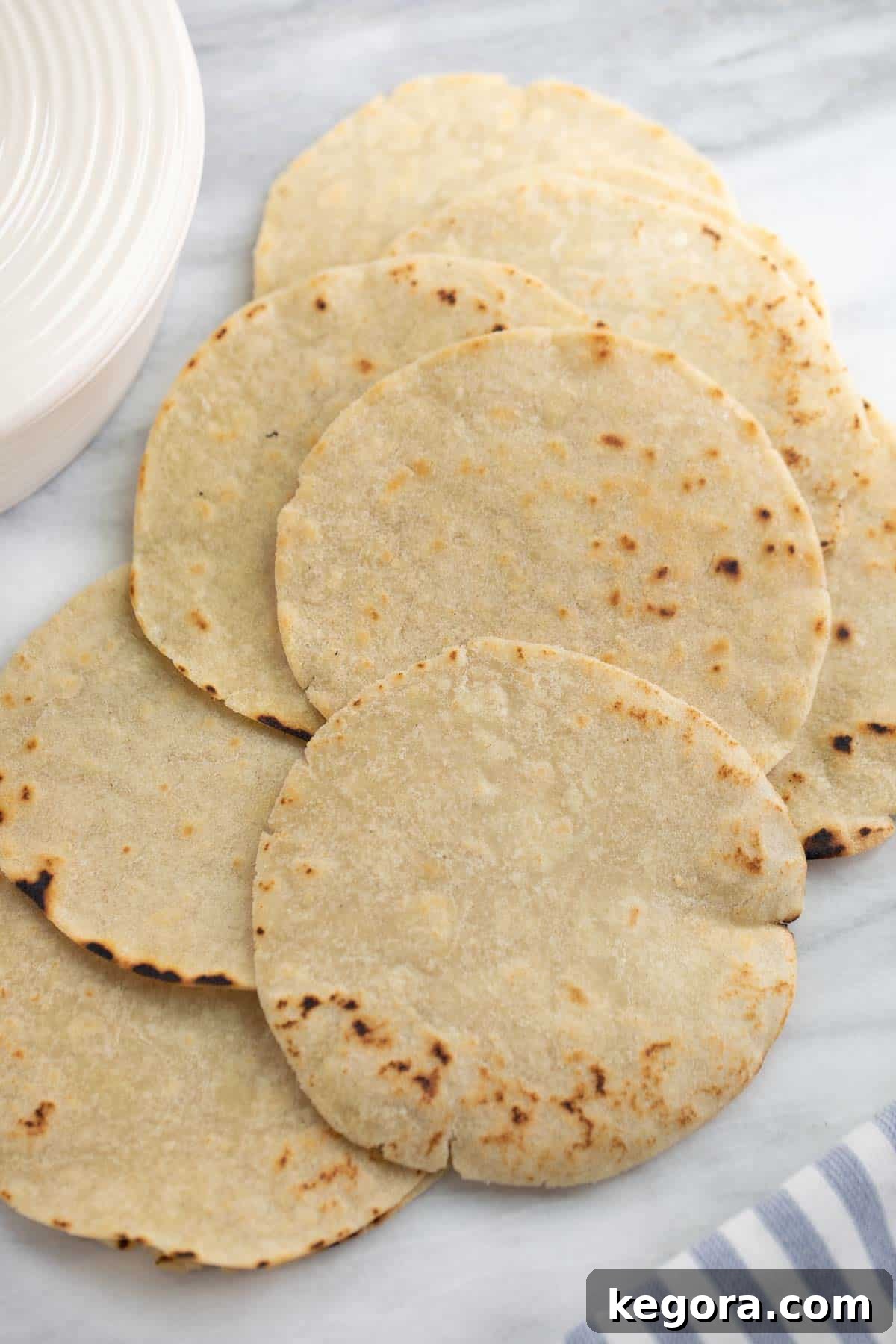 A stack of perfectly cooked gluten-free tortillas on a marble background.
