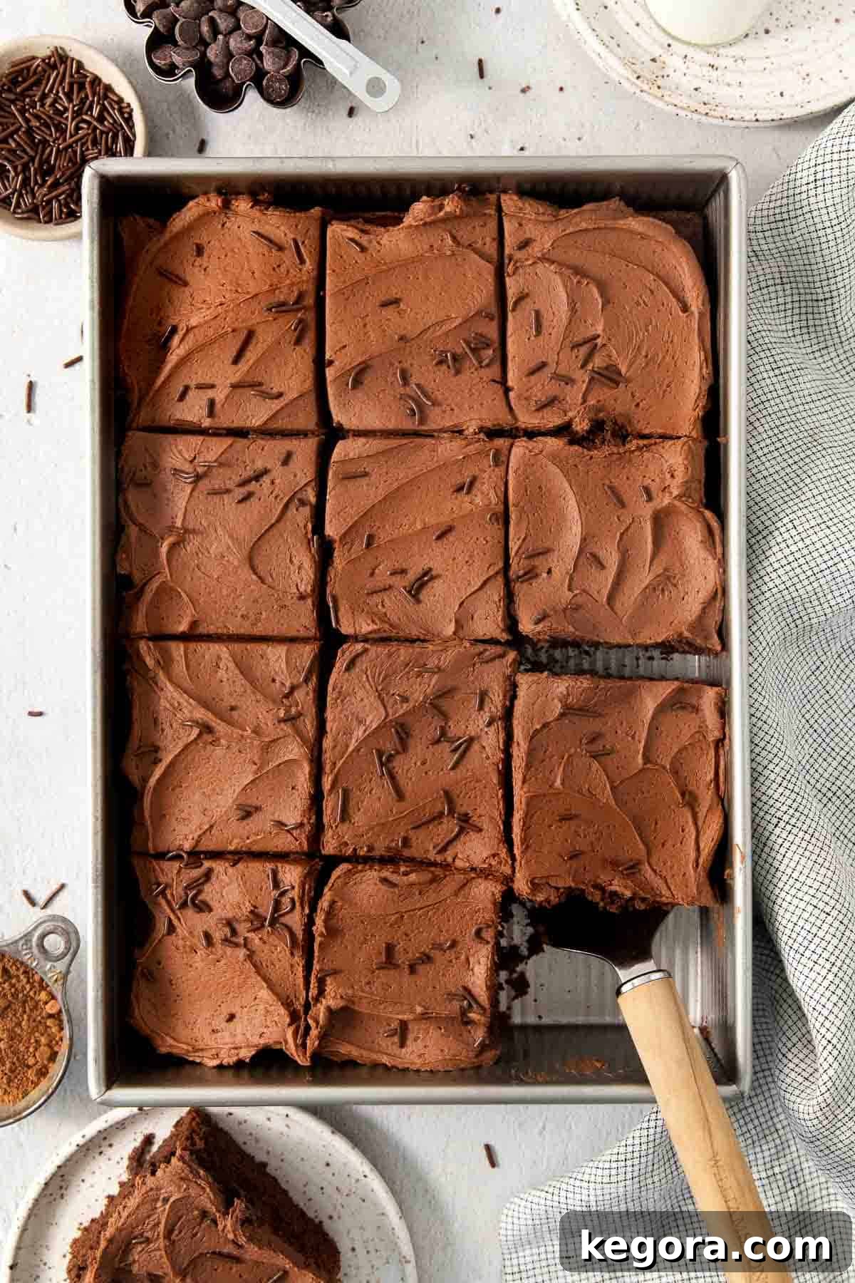 Effortless Gluten-Free Chocolate Masterpiece 8 sliced chocolate cake in the pan with one piece missing and another on the spatula.