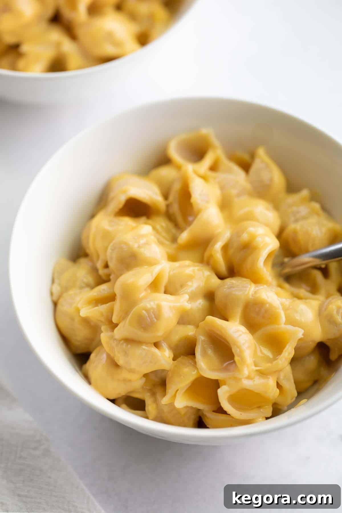 Decadent Gluten-Free Mac and Cheese 7 Delicious oven-baked gluten-free mac and cheese served in a white bowl with a spoon, ready to eat