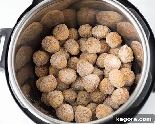 Instant Pot Meatball Pasta Perfection 3 Pressure cooker with frozen meatballs in pot, ready for the next layer of ingredients.