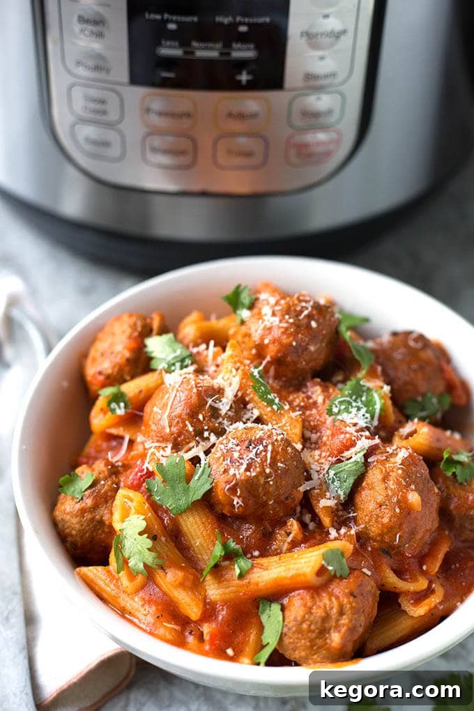 A serving of Instant Pot Meatball Pasta Dinner in a white bowl, with the Instant Pot visible in the background, showcasing a delicious and convenient meal.