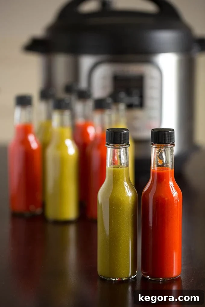 Bottles of green and red hot sauce in front of pressure cooker