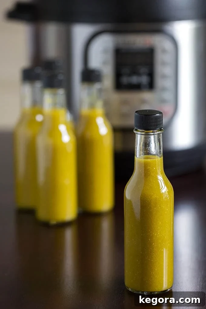 Several bottles of green hot sauce in front of pressure cooker