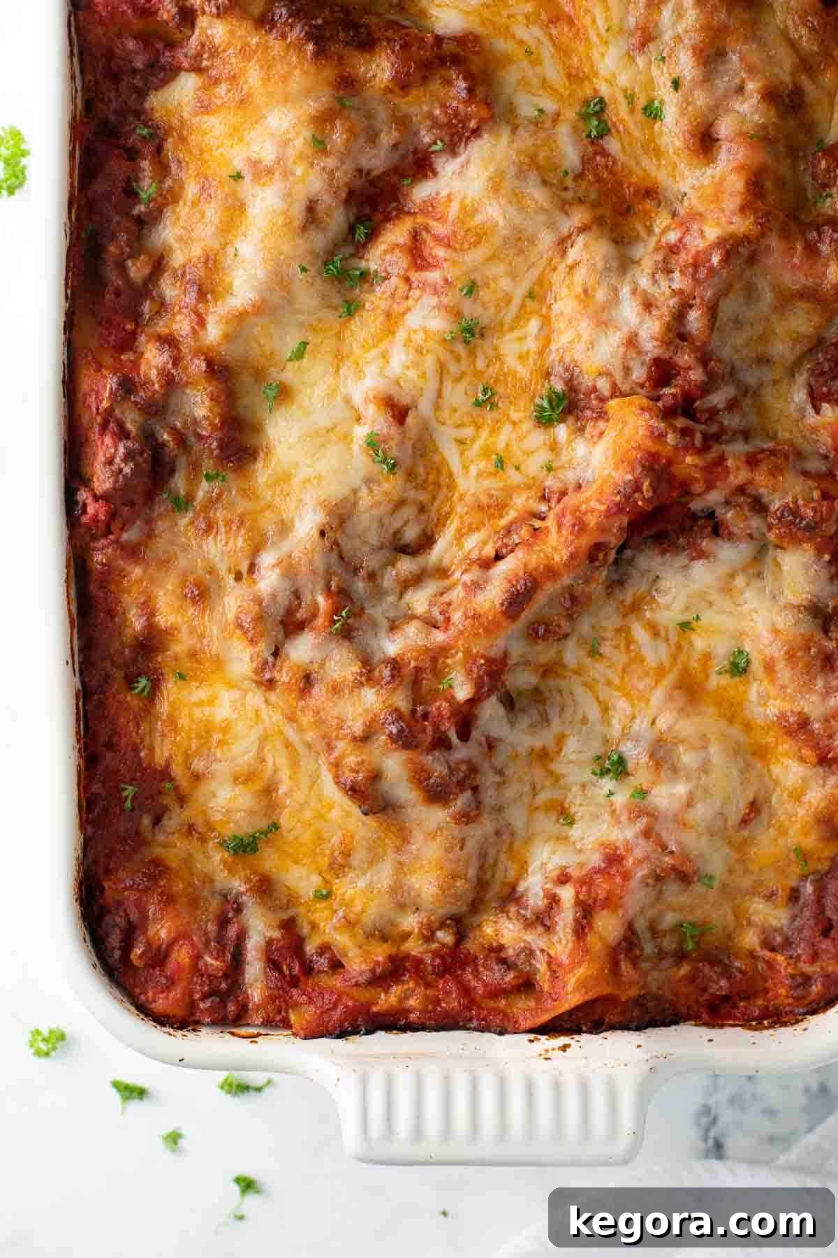 Close-up overhead shot of a golden, bubbly gluten-free lasagna in a white baking dish, ready to be served.