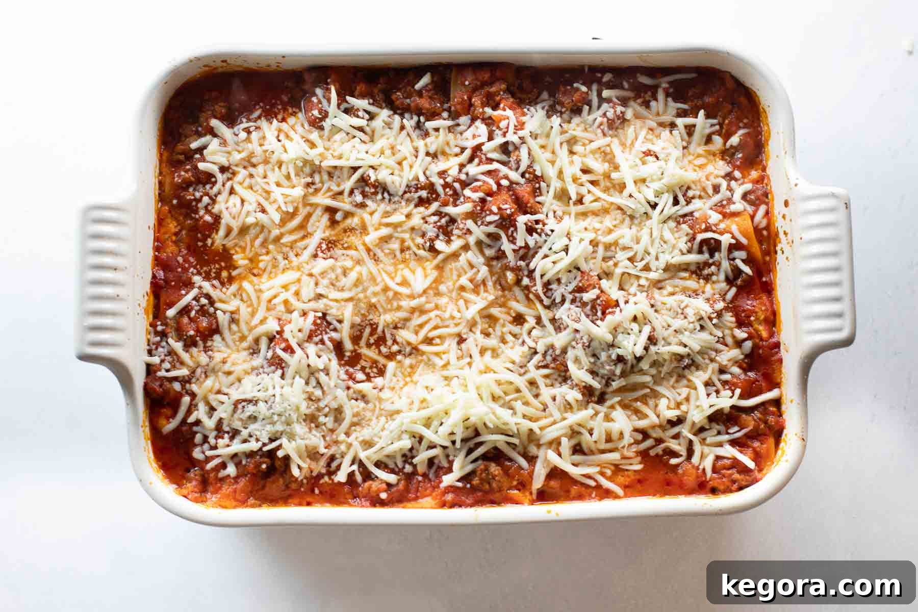 A freshly baked gluten-free lasagna, topped with golden-brown mozzarella cheese and bubbling sauce, in a white baking dish.