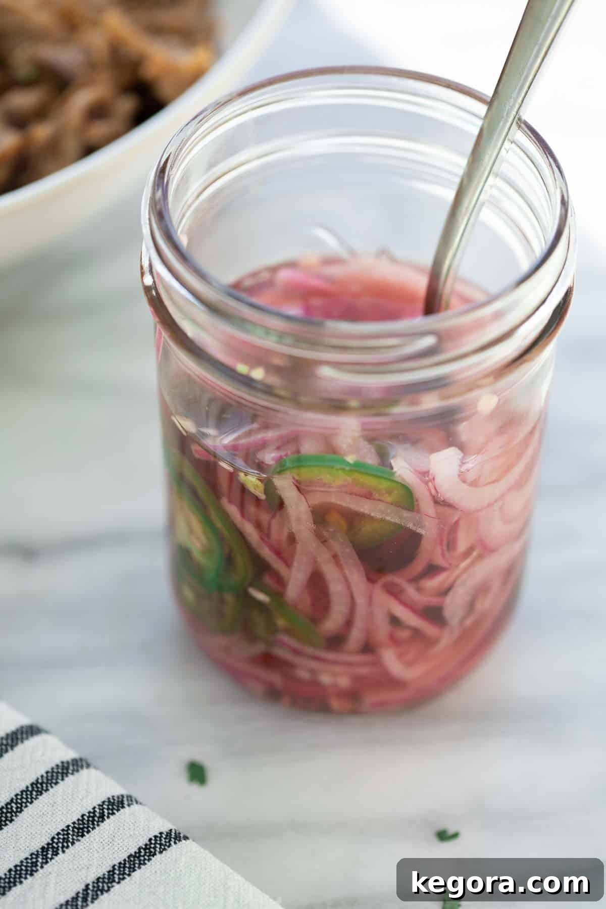 Fork-Tender Sweet Pork Tacos 8 pickled onions in mason jar with fork on marble background
