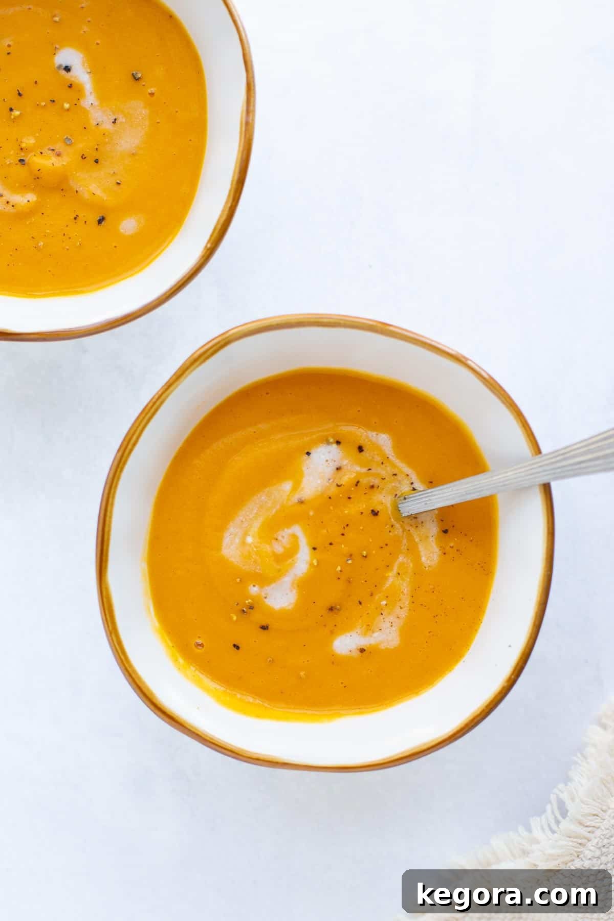 Creamy Roasted Sweet Potato Soup for Comfort Two bowls of creamy roasted sweet potato soup, garnished with a swirl of coconut milk and a sprinkle of black pepper, ready to be served.