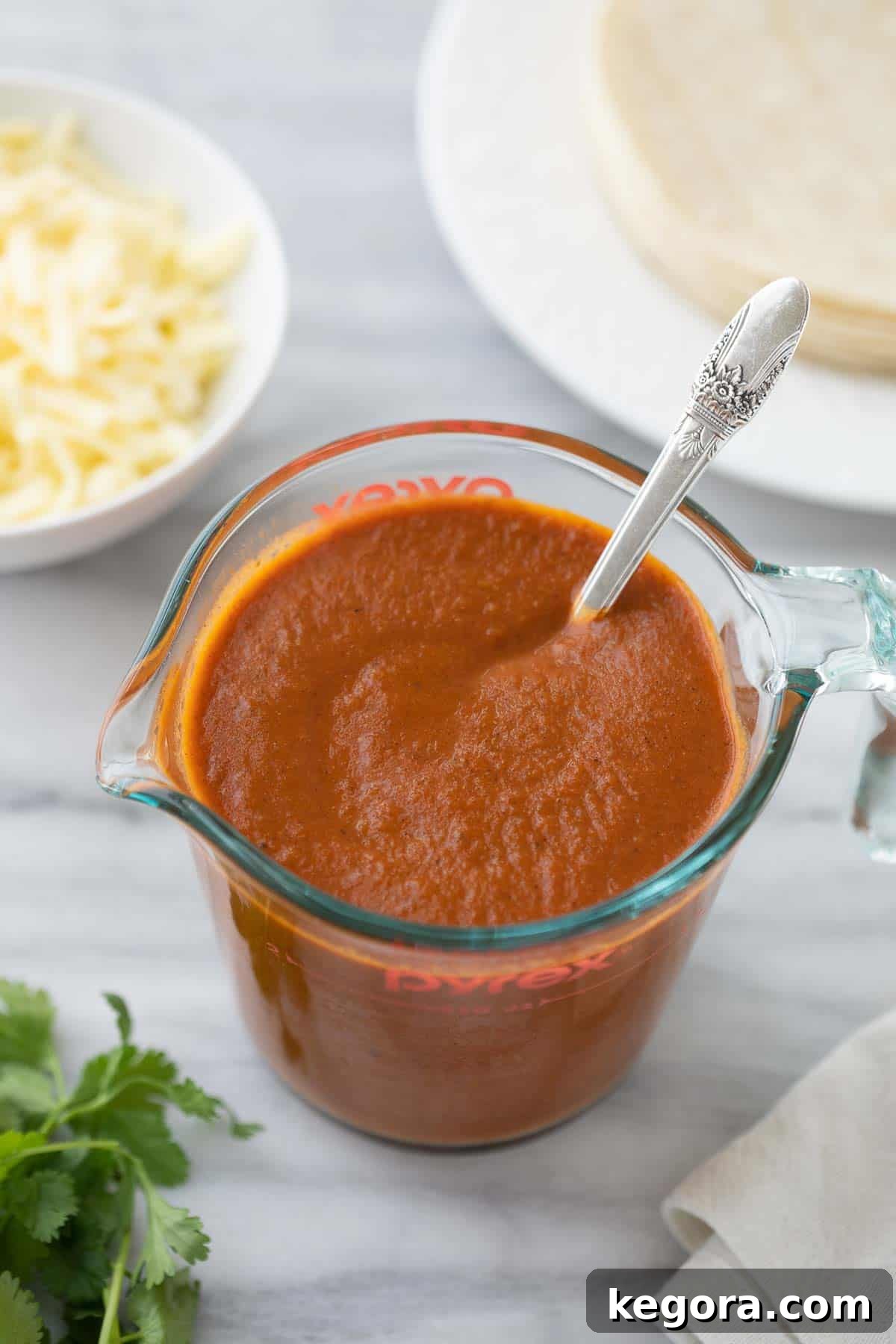 Homemade gluten-free enchilada sauce in a clear glass measuring cup, ready to be used in your favorite Mexican dishes.