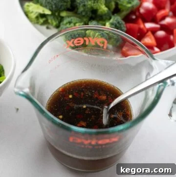 A glass measuring cup filled with a whisked, golden-brown gluten-free stir-fry sauce.