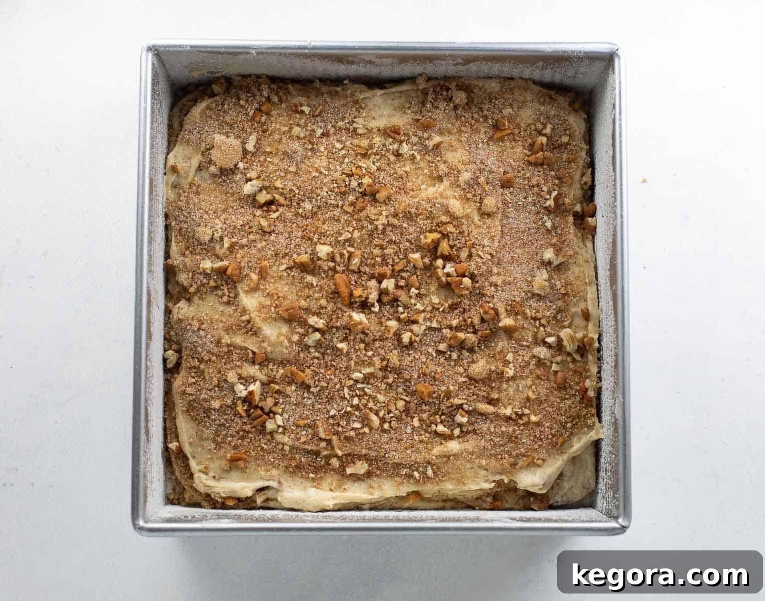 Gluten-free coffee cake batter layered beautifully with a rich cinnamon nut mixture in a prepared baking dish, ready to be baked to perfection.